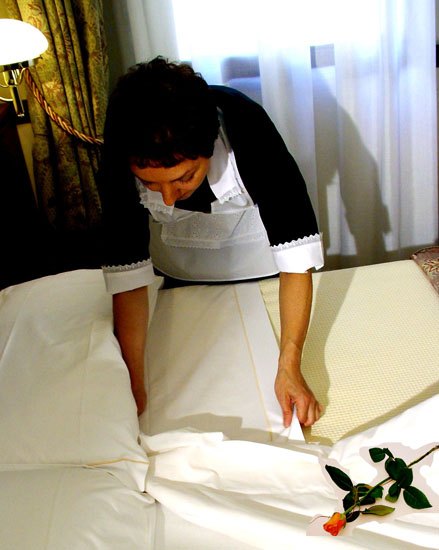 Una collaboratrice prepara un letto con una rosa sulle lenzuola